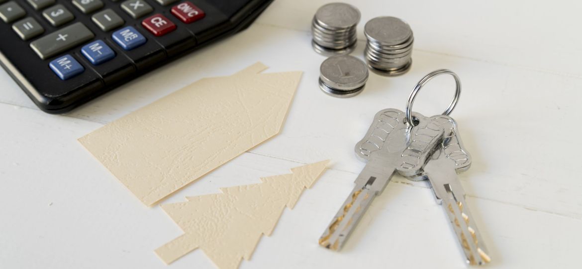 calculator-coins-stack-keys-with-house-tree-paper-cutout-white-wooden-table