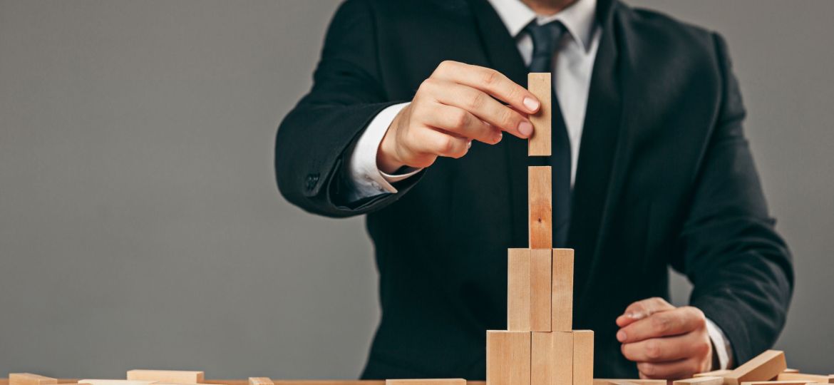Man and wooden cubes on table. Management concept