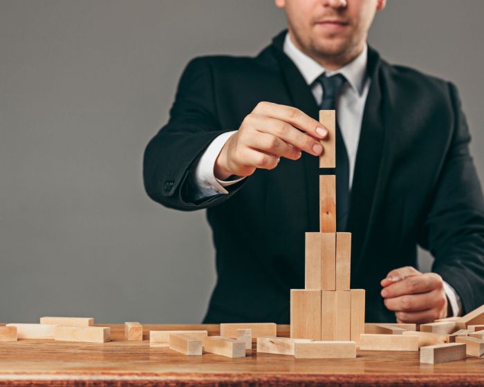 Man and wooden cubes on table. Management concept